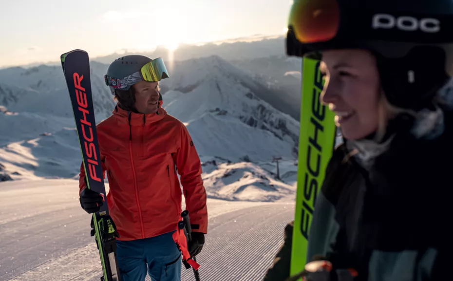 Personen mit Ski bei Sonnenuntergang